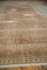 Distressed Kashmir silk carpet with worn knot heads, visible foundation, and muted pink tones.