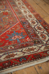 Angled view of a Malayer runner's meandering vine border in red, blue, and ivory.