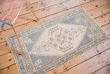 Vintage distressed Oushak rug corner detail, soft faded ink blue border with bronze floral motifs.