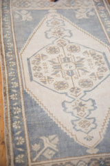 Distressed hexagonal medallion with faded ink blue and beige splayed floral elements.