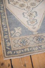 Vintage distressed Oushak rug corner, even wear, faded ink blue field, ivory border, and fringe.