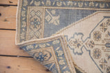 Vintage distressed Oushak rug corner showing original side selvages and faded floral border.