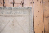 Distressed vintage Oushak rug corner with ivory, silver tones, geometric border, and even wear.