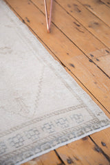 Vintage distressed Oushak rug corner showing ivory wear and geometric silver border.