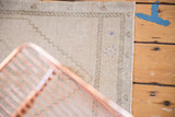 Secured edge and distressed texture of a vintage Oushak rug with subtle purple motifs.