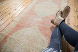 Faded cinnabar, blush, and antique ivory distressed pile of a vintage Oushak rug.