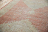 Distressed vintage Oushak rug pile with faded cinnabar, blush, ivory, and visible foundation.
