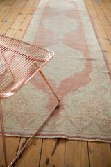 Distressed vintage Oushak runner, with faded blush patterns and worn pile texture along the edge.