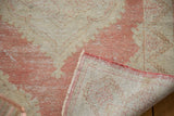 Distressed Oushak runner corner shows worn cinnabar and ivory pile, foundation, secured edge.