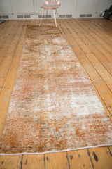 Vintage distressed Oushak runner showing textured pile with copper, ivory, and brown shades.