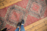 Vintage distressed Oushak runner with geometric hook and latch motifs in cherry red and charcoal.