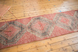 Distressed Oushak runner with repeating cherry red and charcoal geometric guls.