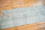 Distressed texture of a vintage overdyed Oushak rug in pale sea foam green and white.