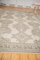 Ornate border and field patterns of the distressed Oushak carpet in sand and coffee.