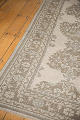 Distressed Oushak carpet's low pile, revealing pale beige, brown, and blue floral motifs.