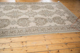 Low pile decorative border and repeating floral patterns in sand beige, brown, and blue-gray.