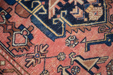 Detail of hand-knotted antique Malayer rug showing geometric lovebird motifs in dusty blush, indigo, and beige.