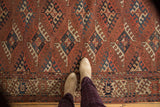 Antique Turkmen carpet's geometric guls, implied lattice, and vibrant border in chestnut, navy, beige.
