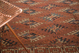 Textural low pile and geometric guls in chestnut, navy, and ivory on an antique Turkmen carpet.