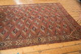 Antique Turkmen carpet's geometric guls and patterned border in chestnut, navy, and beige.