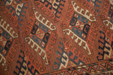 Detailed view of antique Turkmen carpet's geometric guls, showing chestnut, navy, and ivory.