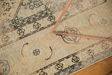 Pale melon, seafoam green, charcoal geometric patterns on distressed Sivas carpet with copper frame.