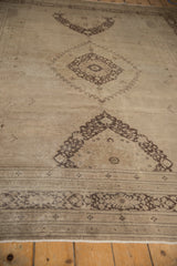 Distressed charcoal brown serrated medallion detail on antique ivory vintage Khorassan carpet.