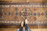 Geometric medallion on antique Serab runner's patinated camel field with blue and red motifs.