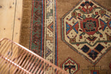 Antique Serab rug's geometric medallion in red, blue, camel, with foundation showing.