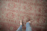 Distressed Oushak rug detail: pale raspberry floral medallions on silver with mostly even wear and faint foundation.