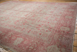 Distressed Oushak carpet's faded silver field with pale raspberry floral motifs and visible wear.