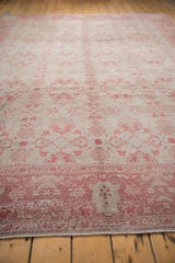 Distressed Oushak carpet: soft raspberry floral patterns, showing mostly even wear and faint foundation.