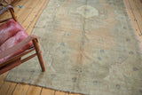 Secured side edge of distressed Oushak rug with low pile and muted olive green.