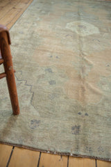 Distressed low pile, olive, beige, apricot tones, and secured selvage on vintage Oushak rug.