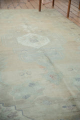 Distressed Oushak rug, faded ivory and apricot tones, with low pile texture.