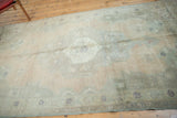 Distressed vintage Oushak carpet in olive green, antique ivory, dusty beige, and faded apricot colors, showcasing its muted tones.