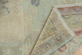 Folded corner of distressed vintage Oushak rug with plush low pile and intact selvage.