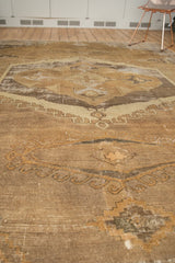 Distressed Oushak carpet detail, showing worn coffee brown, sand, and charcoal patterns with texture.