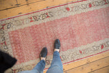 Distressed cherry red Oushak runner with delicate boteh motif, visible wear, and ivory border.