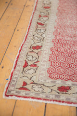 Distressed Oushak runner detail: cherry red lattice pattern, ivory floral border, and wear.