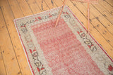 Distressed cherry red Oushak runner showing field pattern, ivory floral border, and light foundation wear.