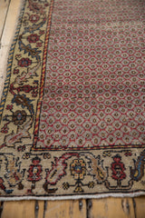 Distressed raspberry red lattice field and antique ivory vine border on Oushak rug.