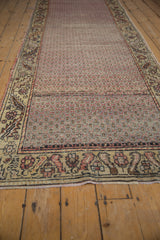 Distressed Oushak rug runner's intricate lattice field and meandering vine border in muted tones.
