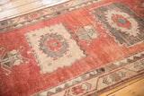 Textured cherry red and charcoal medallion pattern on vintage distressed Oushak rug runner.