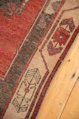Distressed Oushak runner's secured edge with cherry red abrashes and geometric beige border.