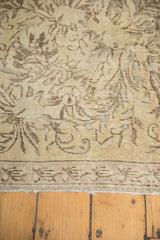 Ornamented European-inspired pattern in beige and brown with visible wear on vintage Sparta rug edge.