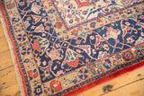Vintage distressed Laristan carpet corner with low pile, navy blue arabesques, and faux fringe.