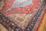 Distressed Laristan rug with red field, delicate vinery, floral palmettes, and navy arabesque border.