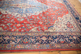 Distressed Laristan rug showing cherry red field's vinery and navy blue arabesque border.