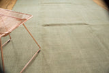 Distressed Oushak carpet in pale sea foam green with visible textural variations.
